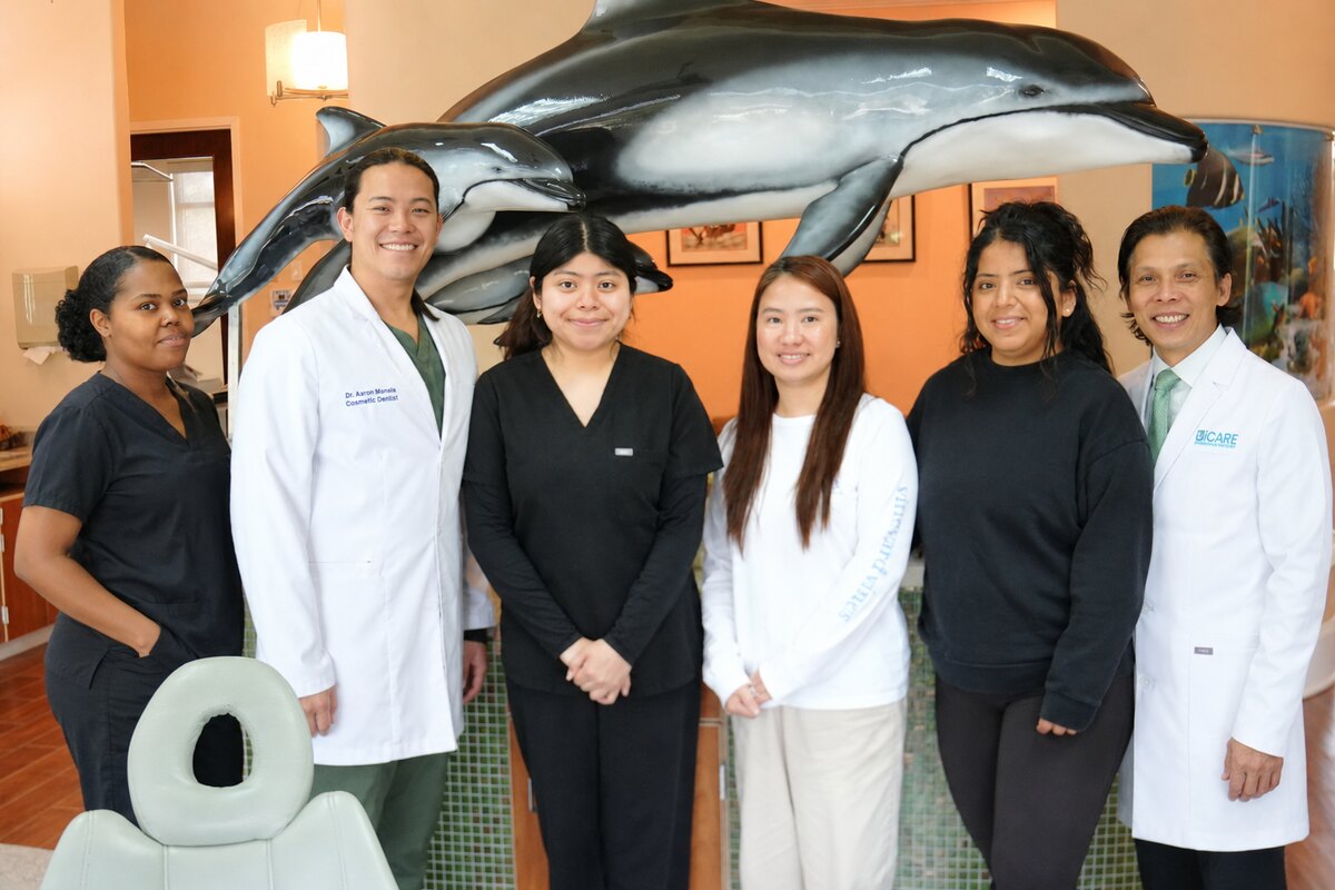 iCare Orthodontics and Dentistry team standing together inside the Norcross office in front of the dolphin display